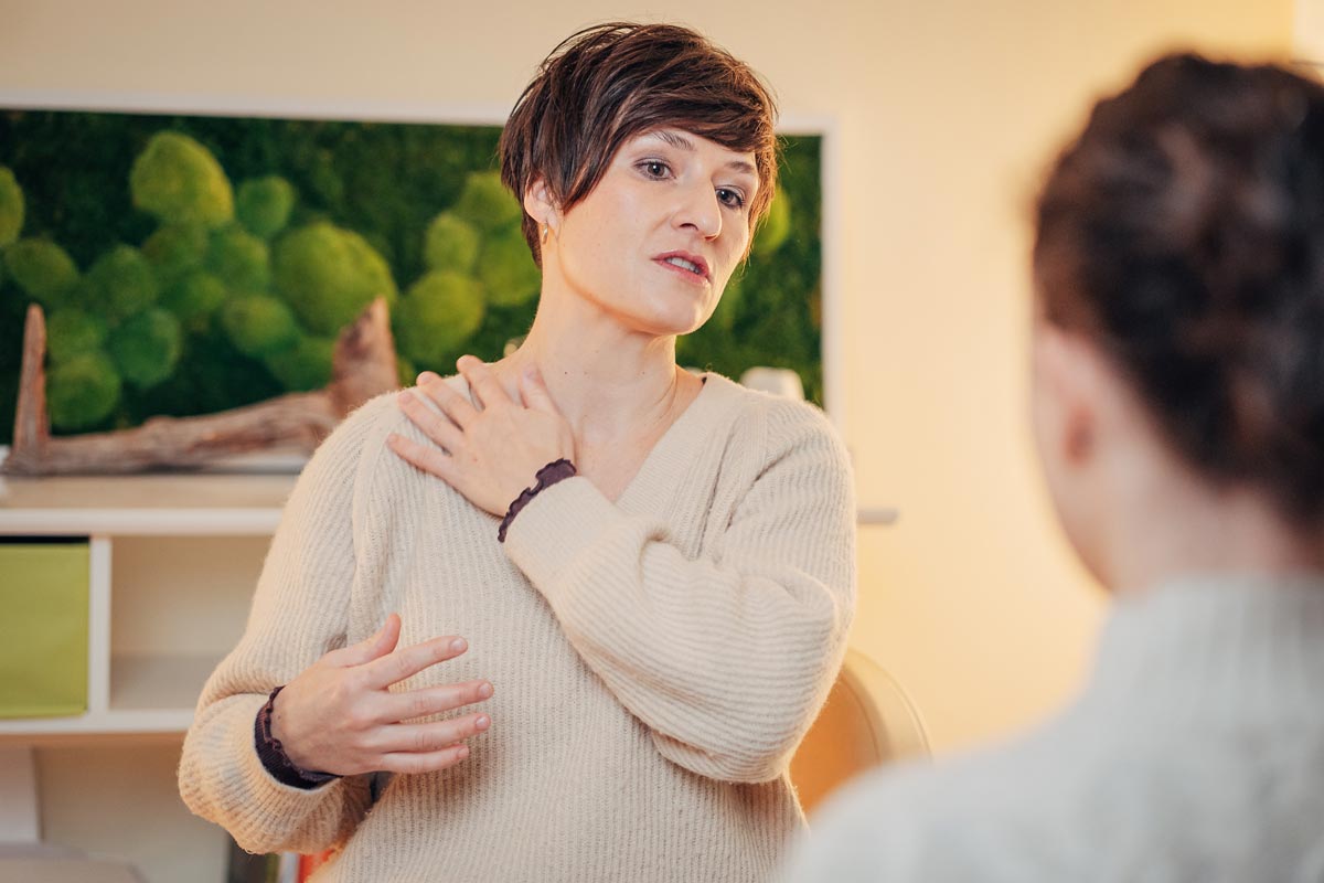 Osteopathin Sally Lindemann demonstriert an der eigenen Schulter die Zusammenhänge in der Körperstrukturen.